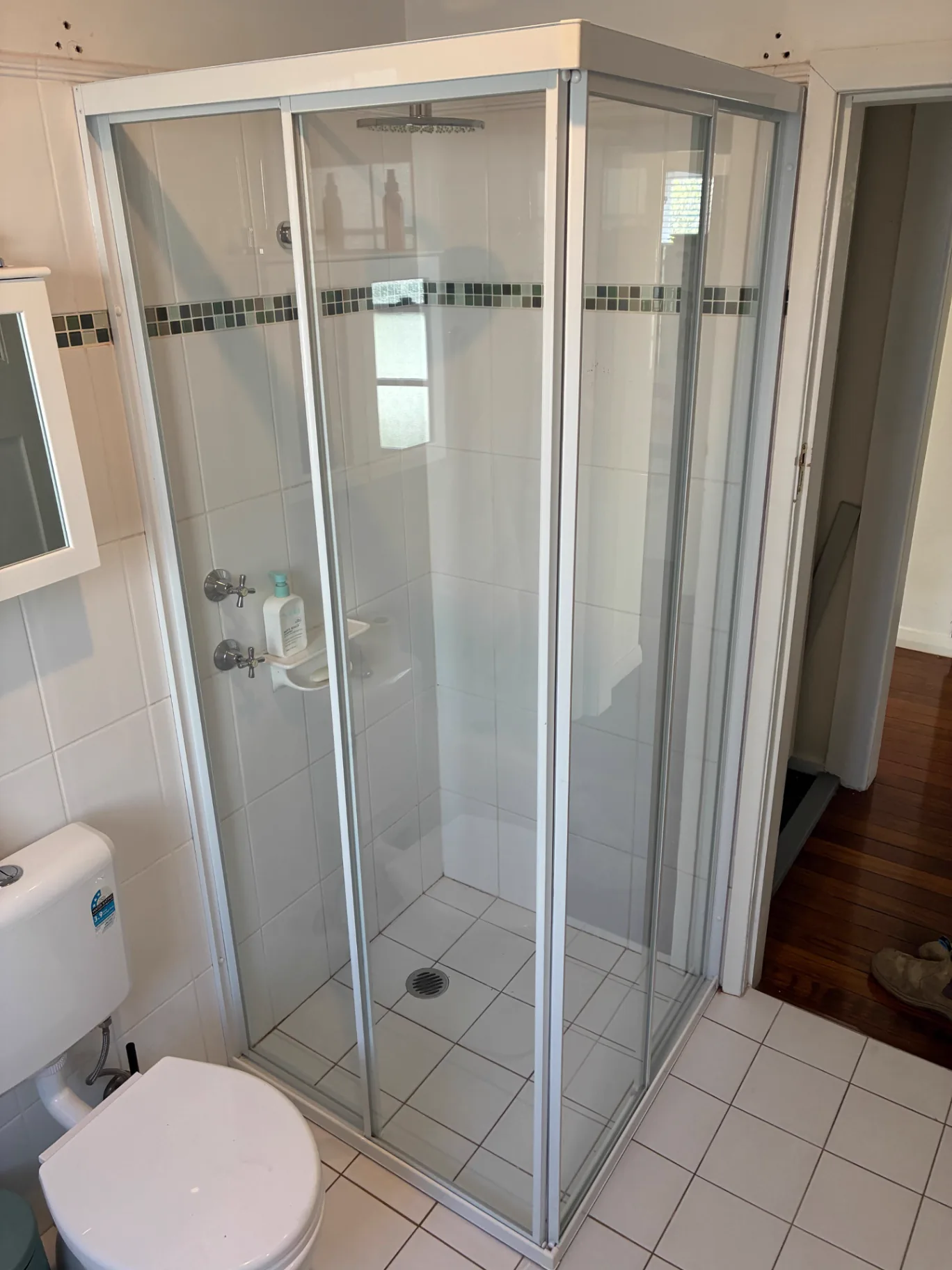 Custom fully framed shower enclosure with white framing installed by Pinnacle Glass & Timber