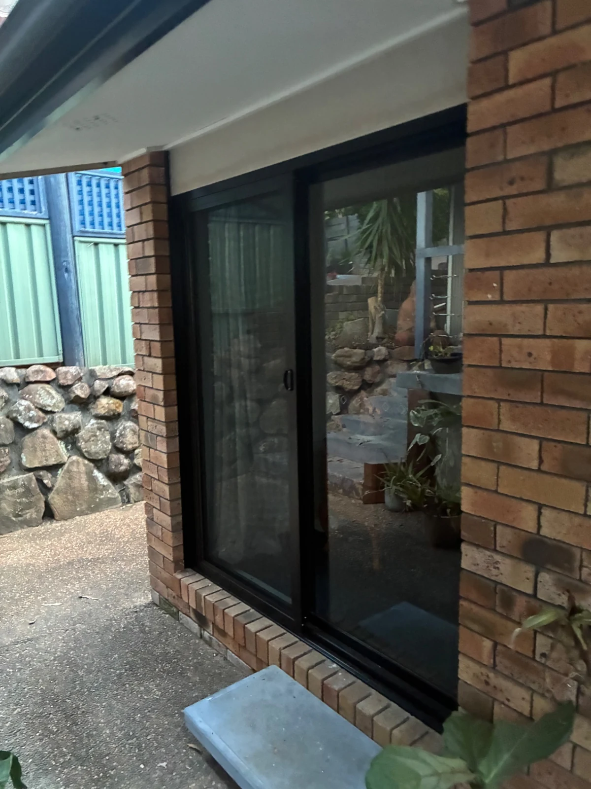 Black-framed sliding glass door in an exterior brick wall